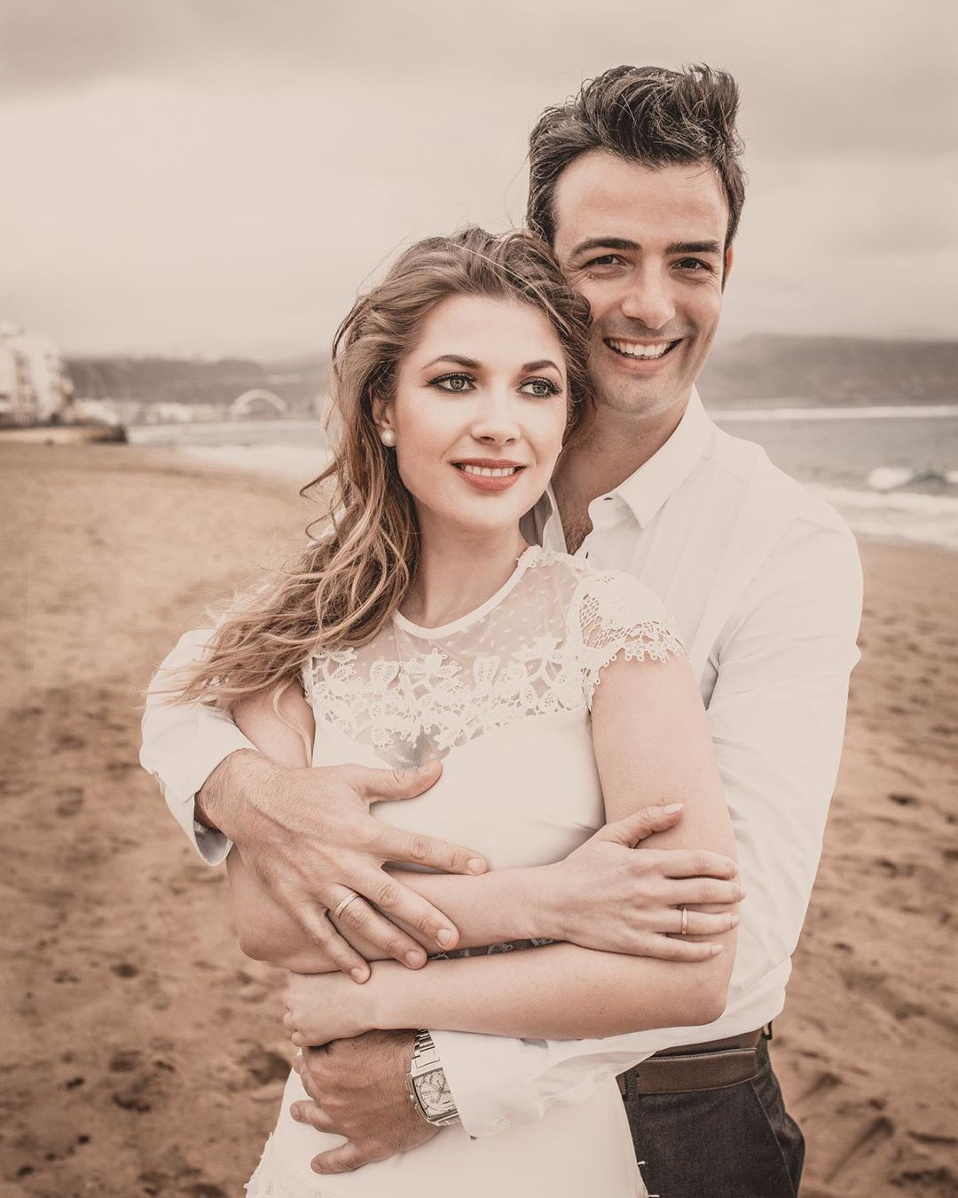 A bride and groom hugging on the beach.