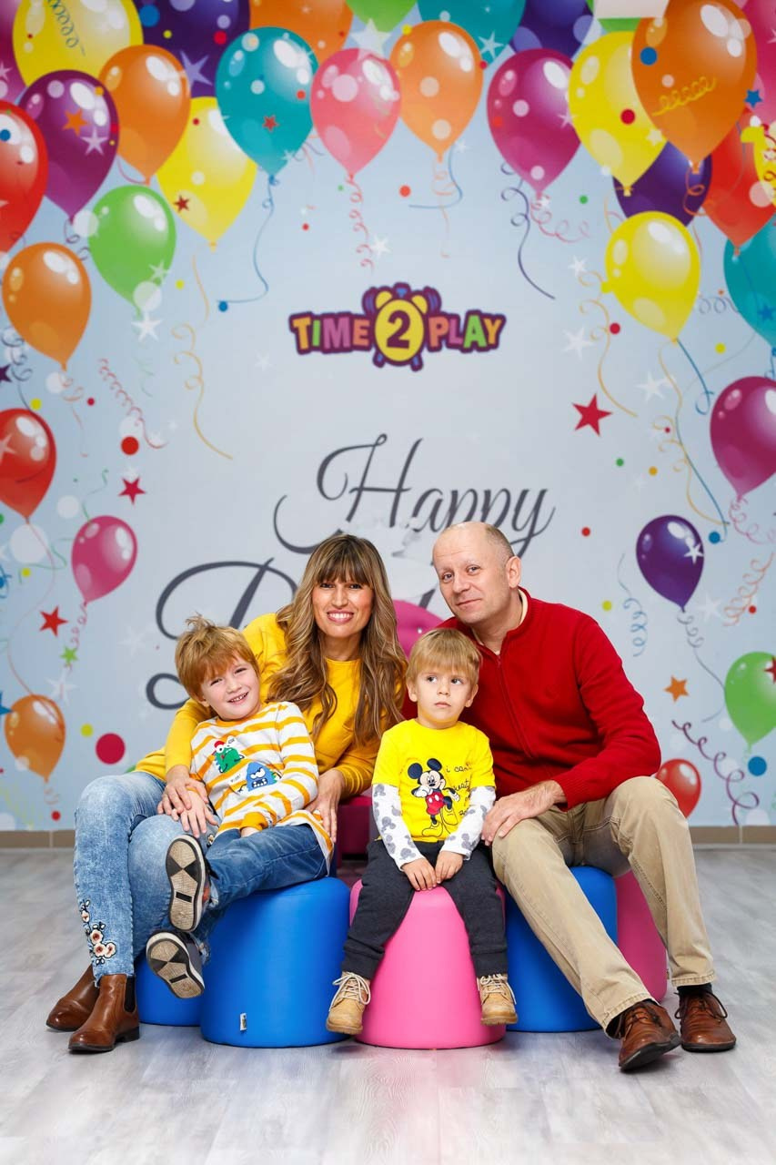 Porodična fotografija na dečjem rođendanu na pozadini od balona.