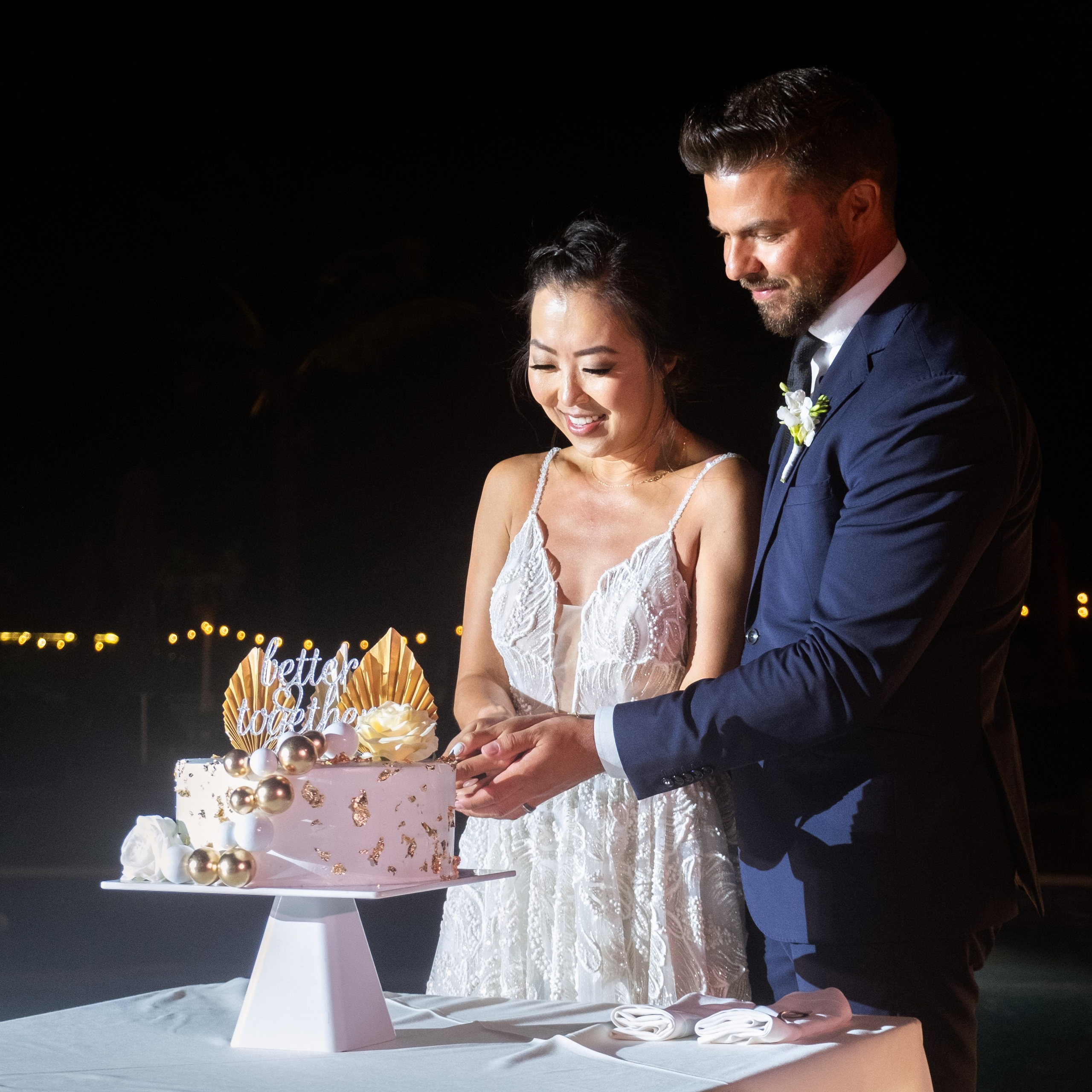 Bride and groom cutting their wedding cake during a poolside reception at Planet Hollywood Cancun.