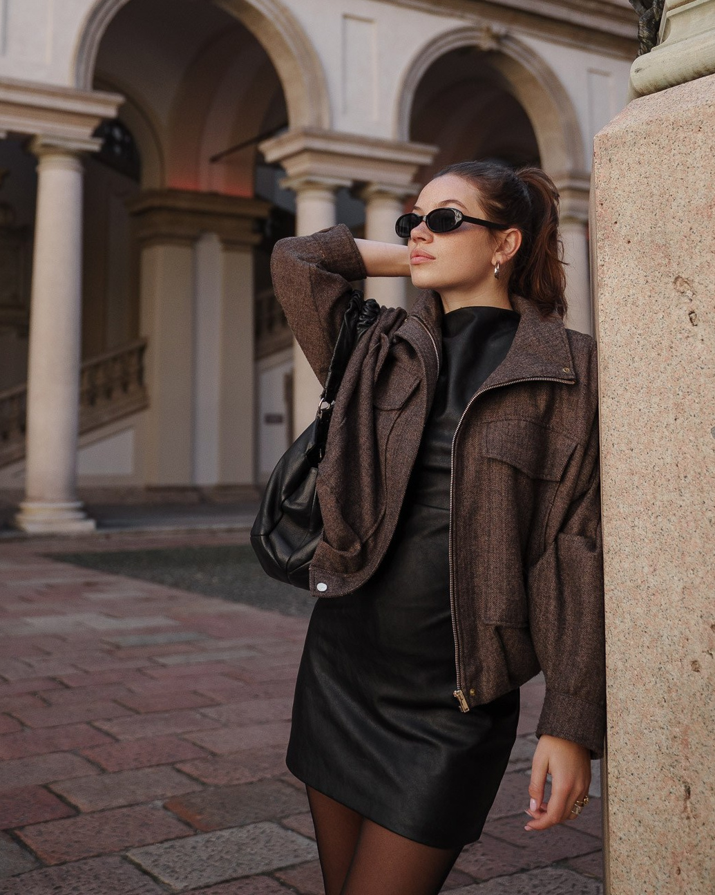 Female model leaning against stone pillar at historic Milan building