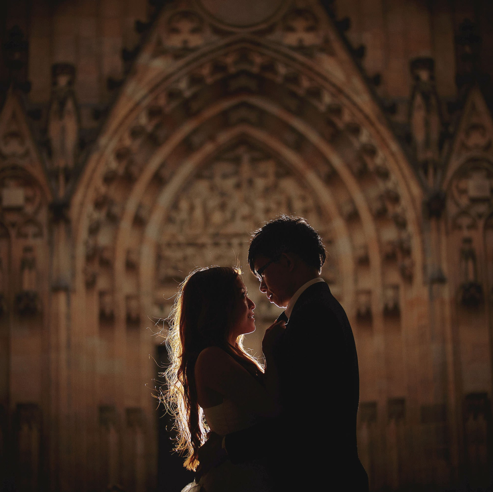 Smiling blonde-haired Swiss bride smiles lovingly towards her Italian groom as he looks towards the camera at a garden in Prague. 