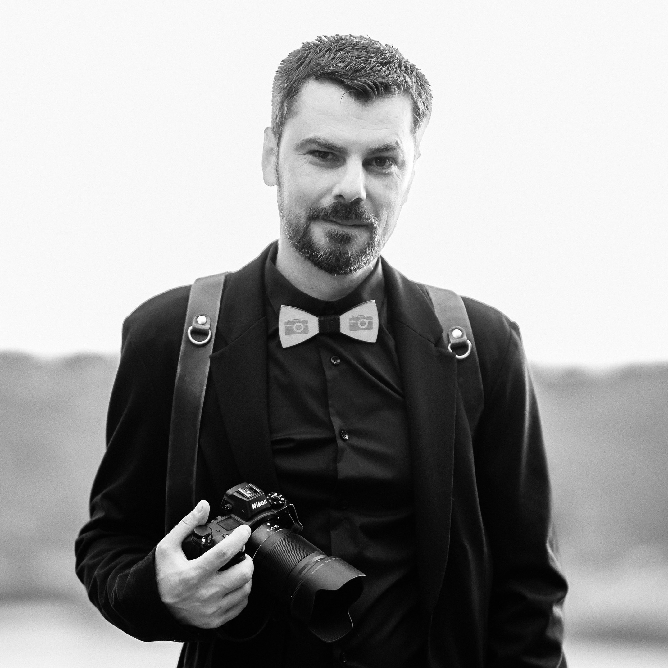 Fotografo di matrimoni professionista in camicia bianca con una fotocamera reflex, pronto a catturare momenti indimenticabili e trasformarli in ricordi eterni.