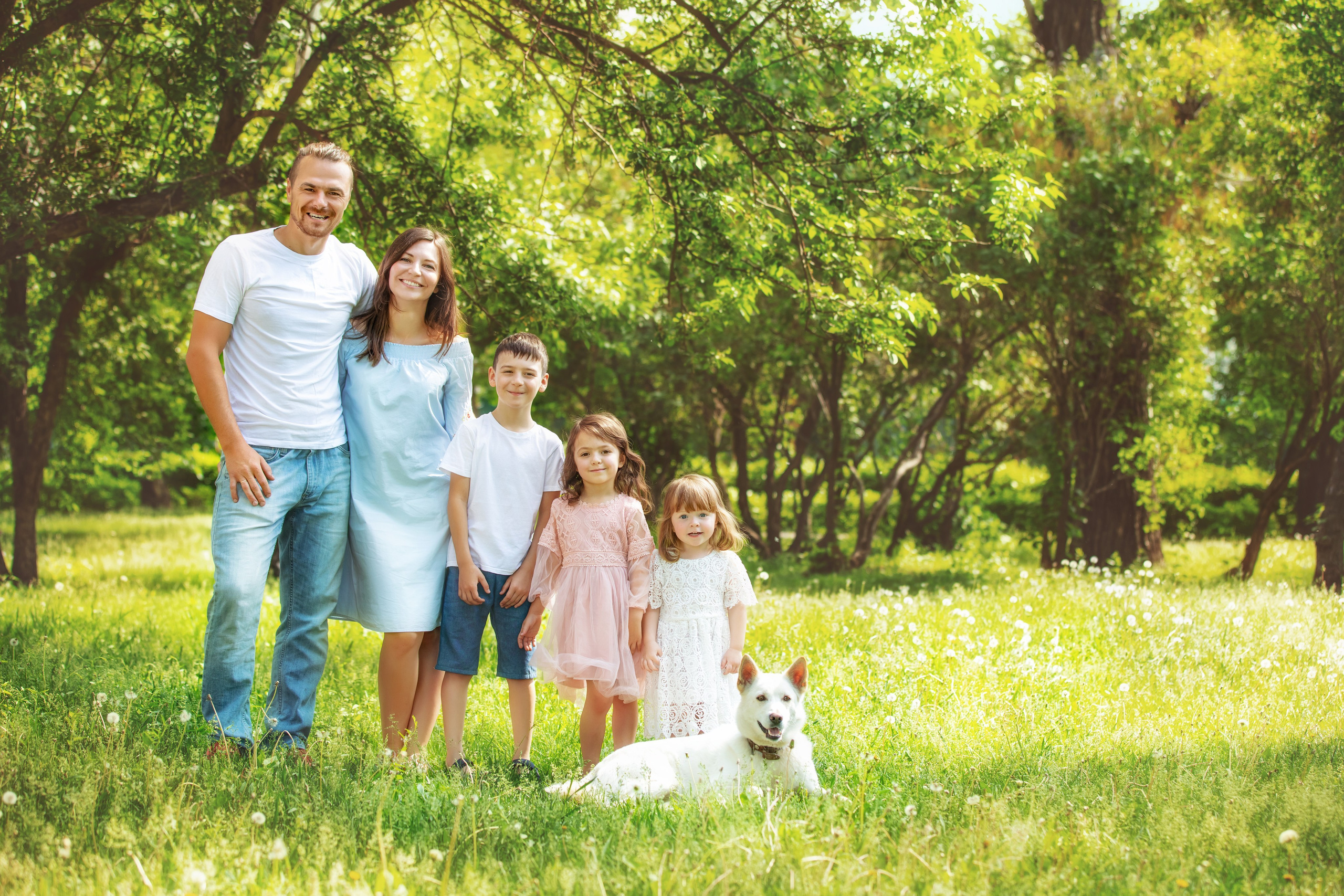 Portrait de famille en plein air avec parents, enfants et chien dans un parc ensoleillé
