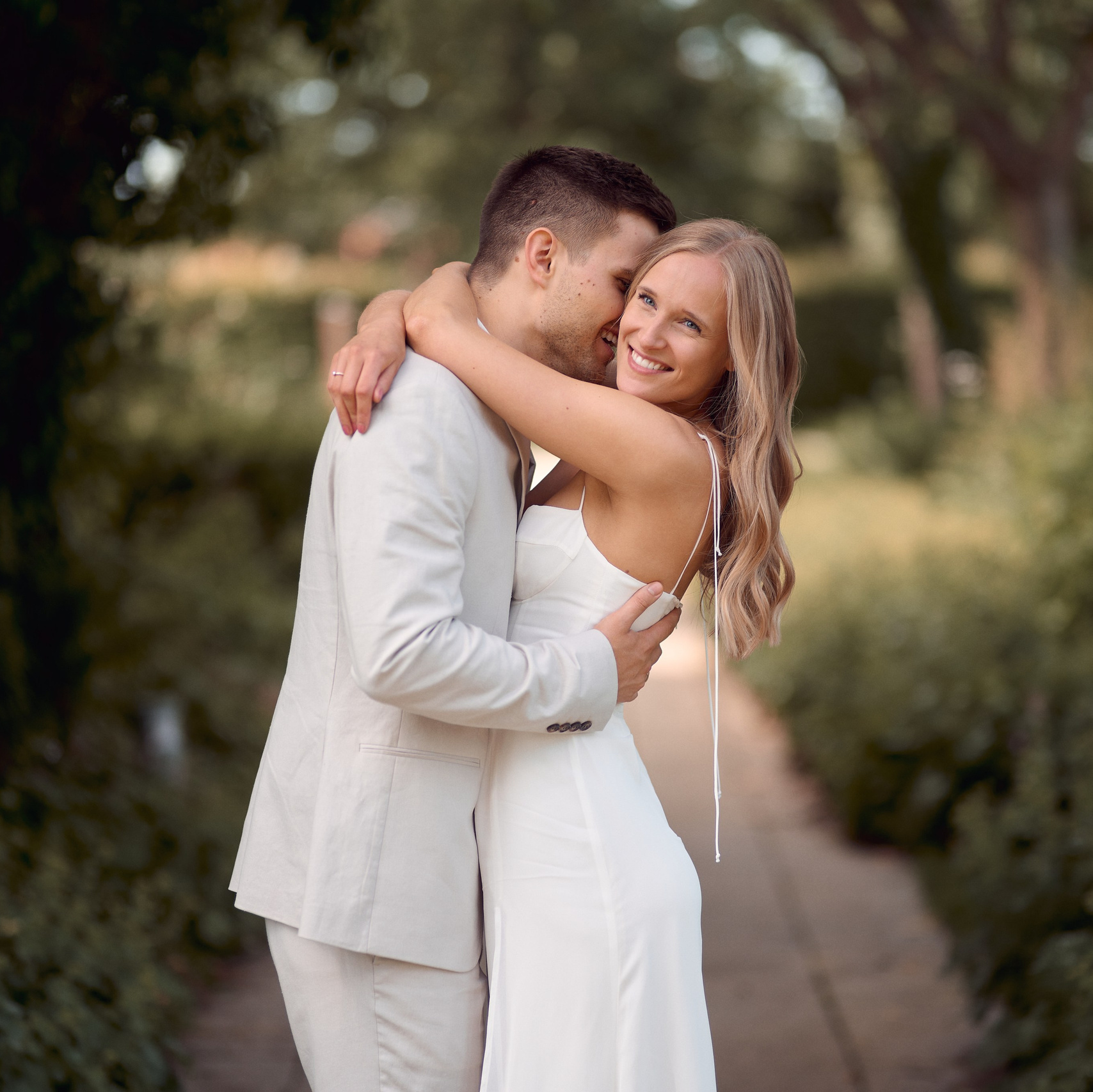 Lachendes Brautpaar umarmt sich liebevoll beim Hochzeitsshooting im Kurpark in Bad Saulgau, fotografiert von Hochzeitsfotograf Alex Fetter.