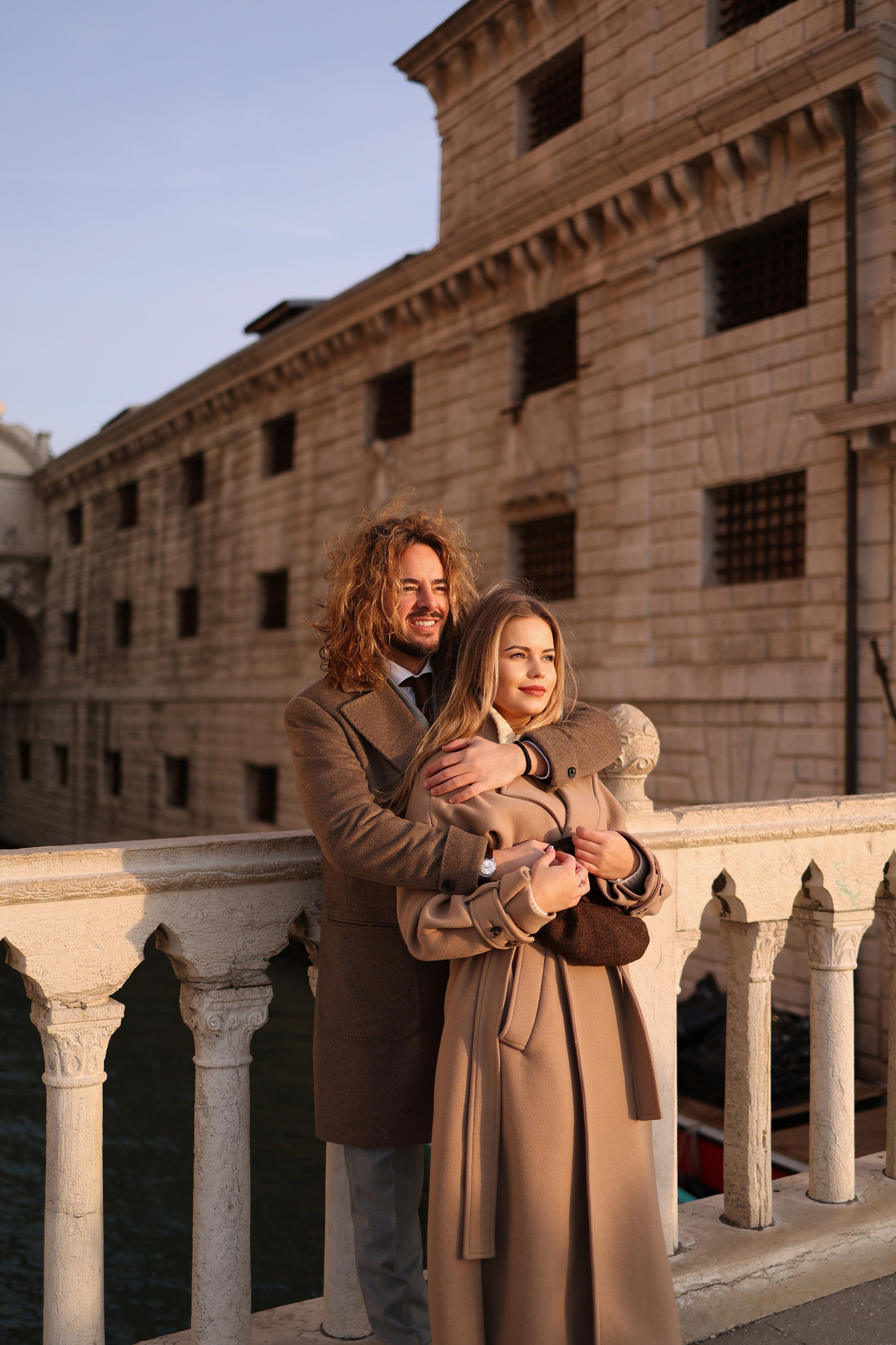 A couple embracing on a stone bridge in Venice during winter