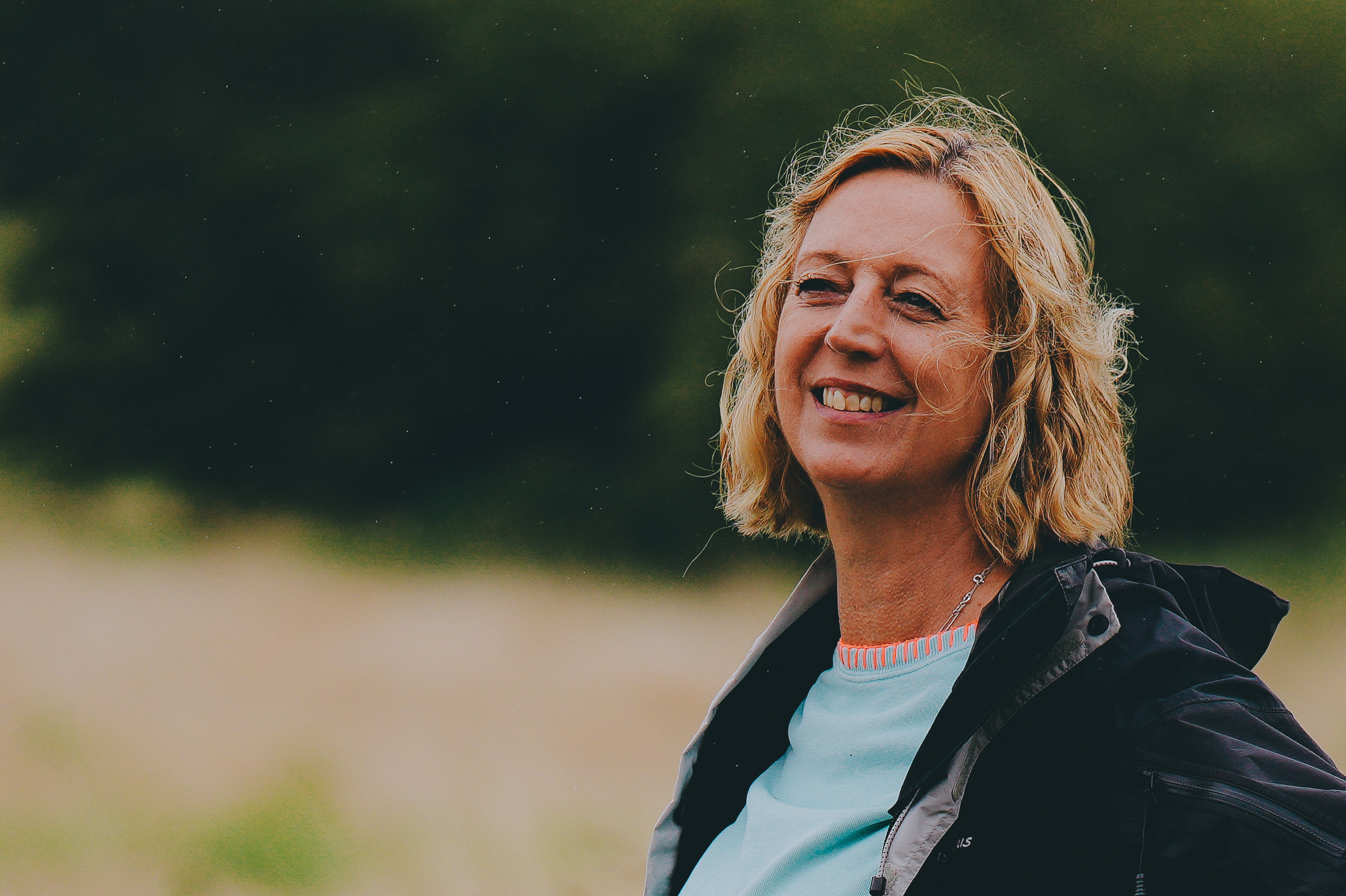 A lady with wavy hair smiling. Feedback on Iyengar yoga lessons.