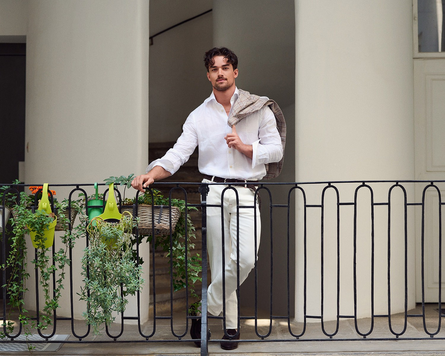 Herrenmode Fotografie Wien – Mann im weißen Hemd lehnt stilvoll an einer Balustrade.