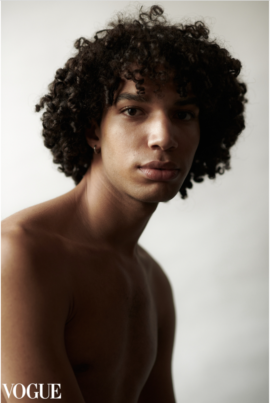 Portretfoto een jonge man met donkere krullen foto op een witte achtergrond in mijn studio.