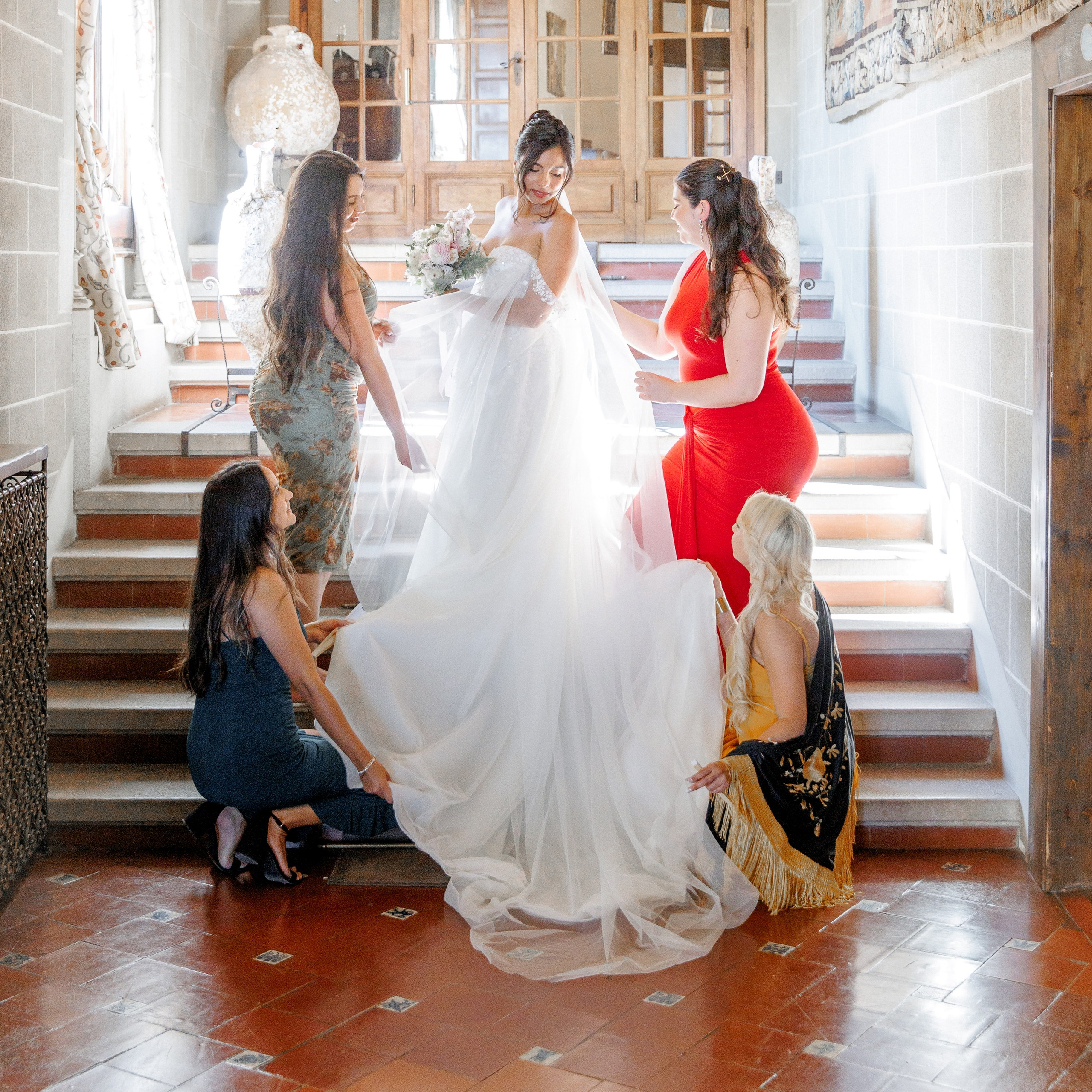 The bride surrounded by bridesmaids on the staircase at La Baronia before the ceremony