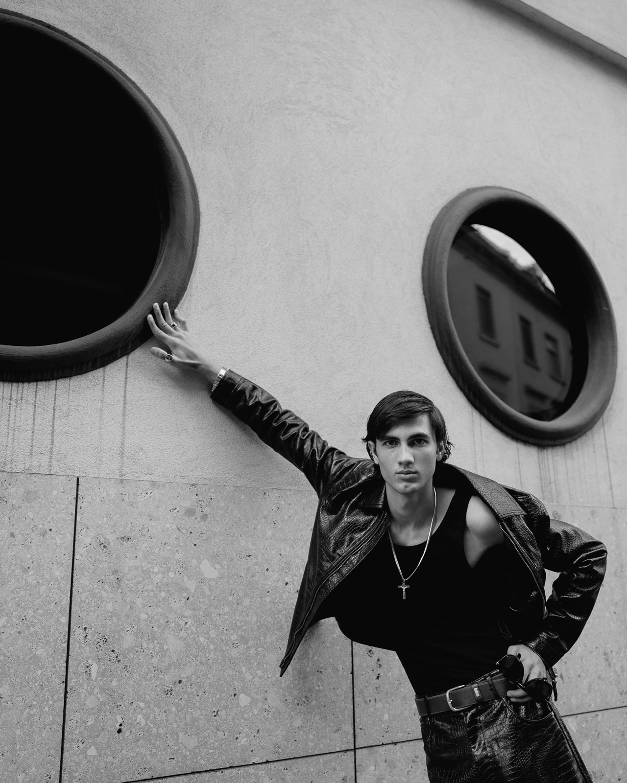 Male model in leather jacket posing against circular windows
