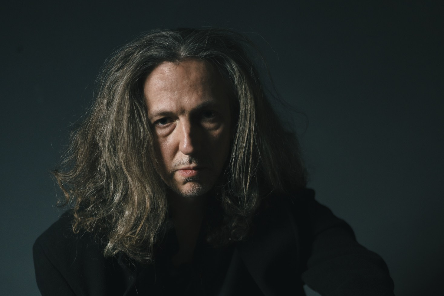 Мужчина с длинными волосами в чёрном, драматичный свет — художественный портрет, фотосессия Дрезден