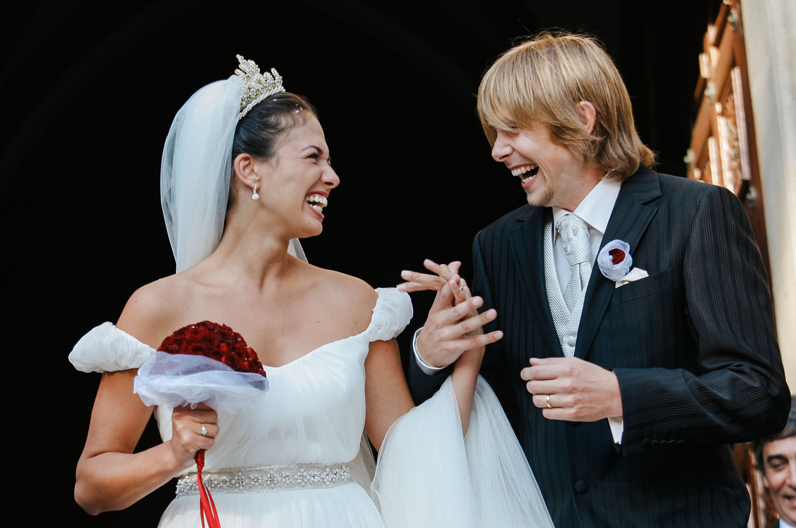 Unforgettable moment: bride and groom smiling, holding hands after rice and flower toss at historic Prague cathedral
