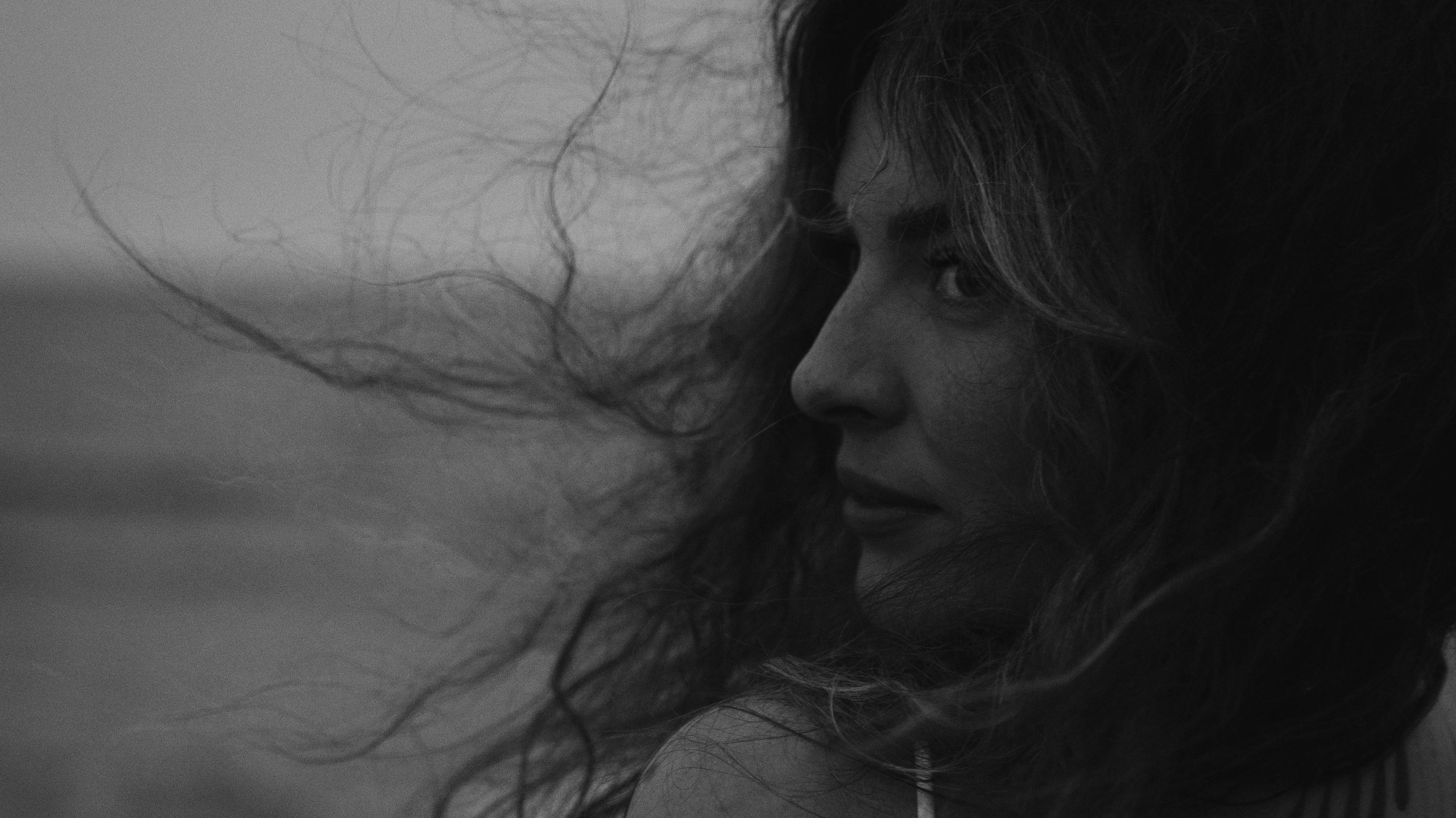 Černo-bílá fotografie ženy blízko, oči, vlasy