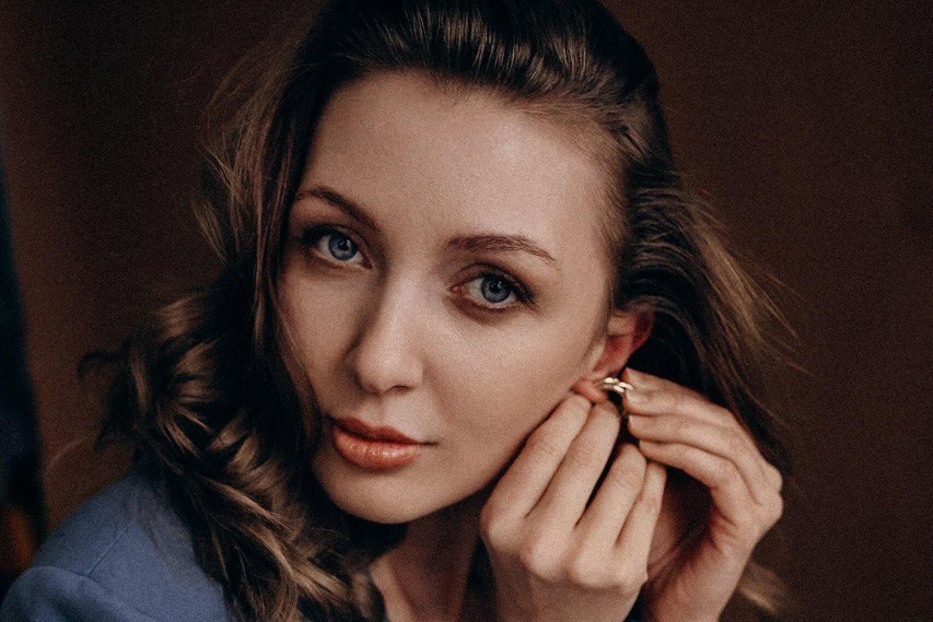 Einzelfotografie in Nürnberg – natürliches und stilvolles Portrait einer Frau beim Anlegen von Schmuck, aufgenommen bei einem professionellen Portraitshooting.