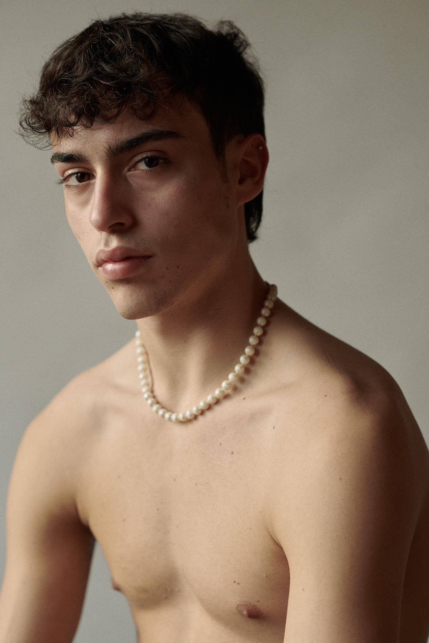 Best portrait photographer in Amsterdam, portrait of a young man with a pearl necklace 