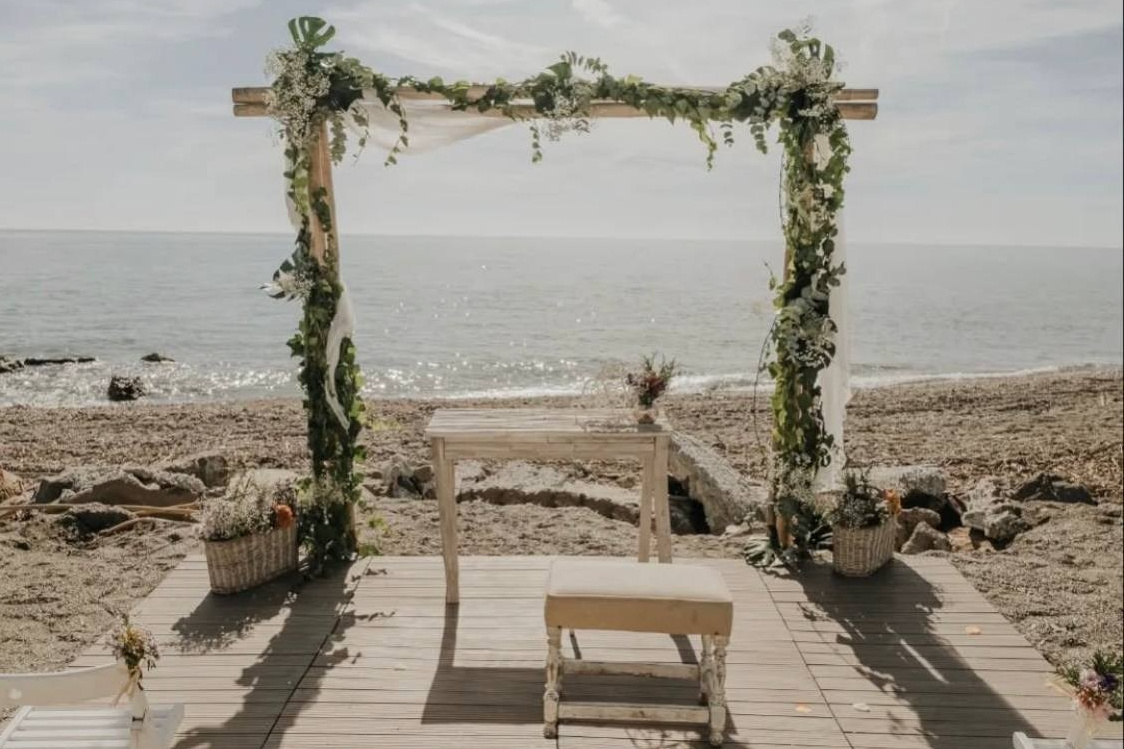 Beach wedding ceremony with arch and chairs