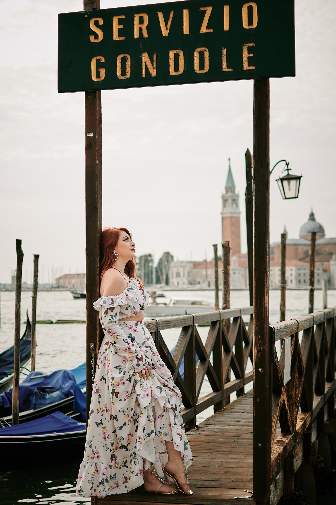 The young woman serenely as she poses on a bridge over a quiet canal in Venice. The soft light of early morning illuminates the scene, casting a warm glow over the cityscape