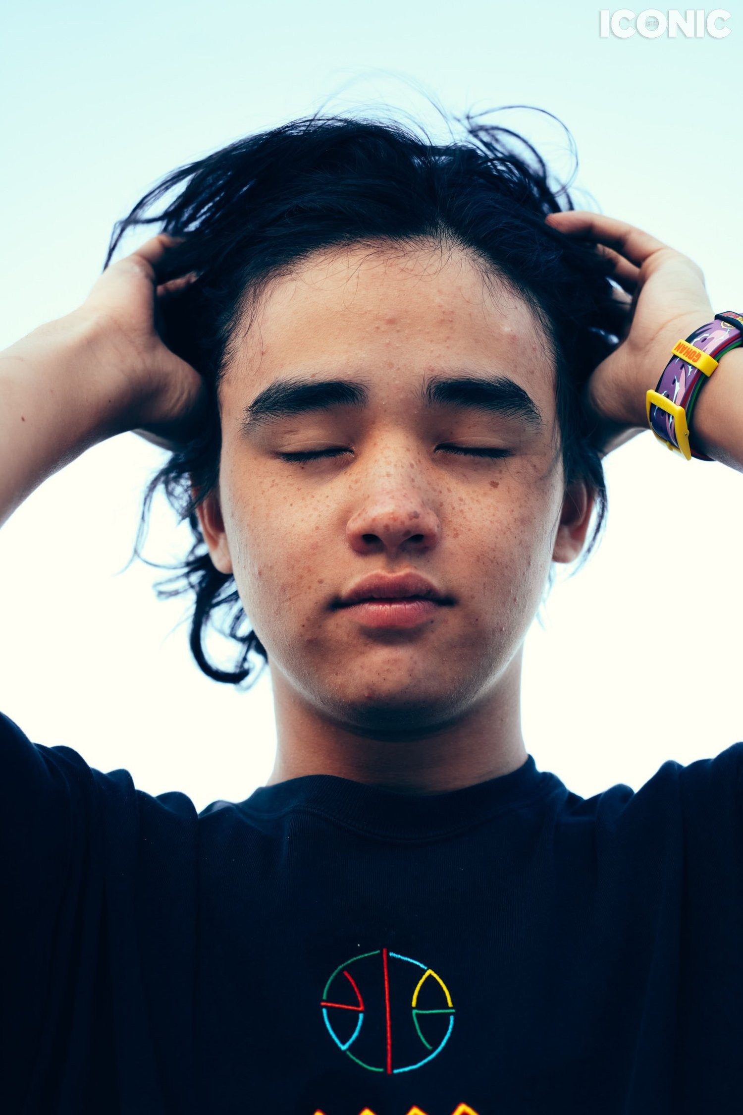 Teenager photography. Boy with the close eyes holding his head and hair.