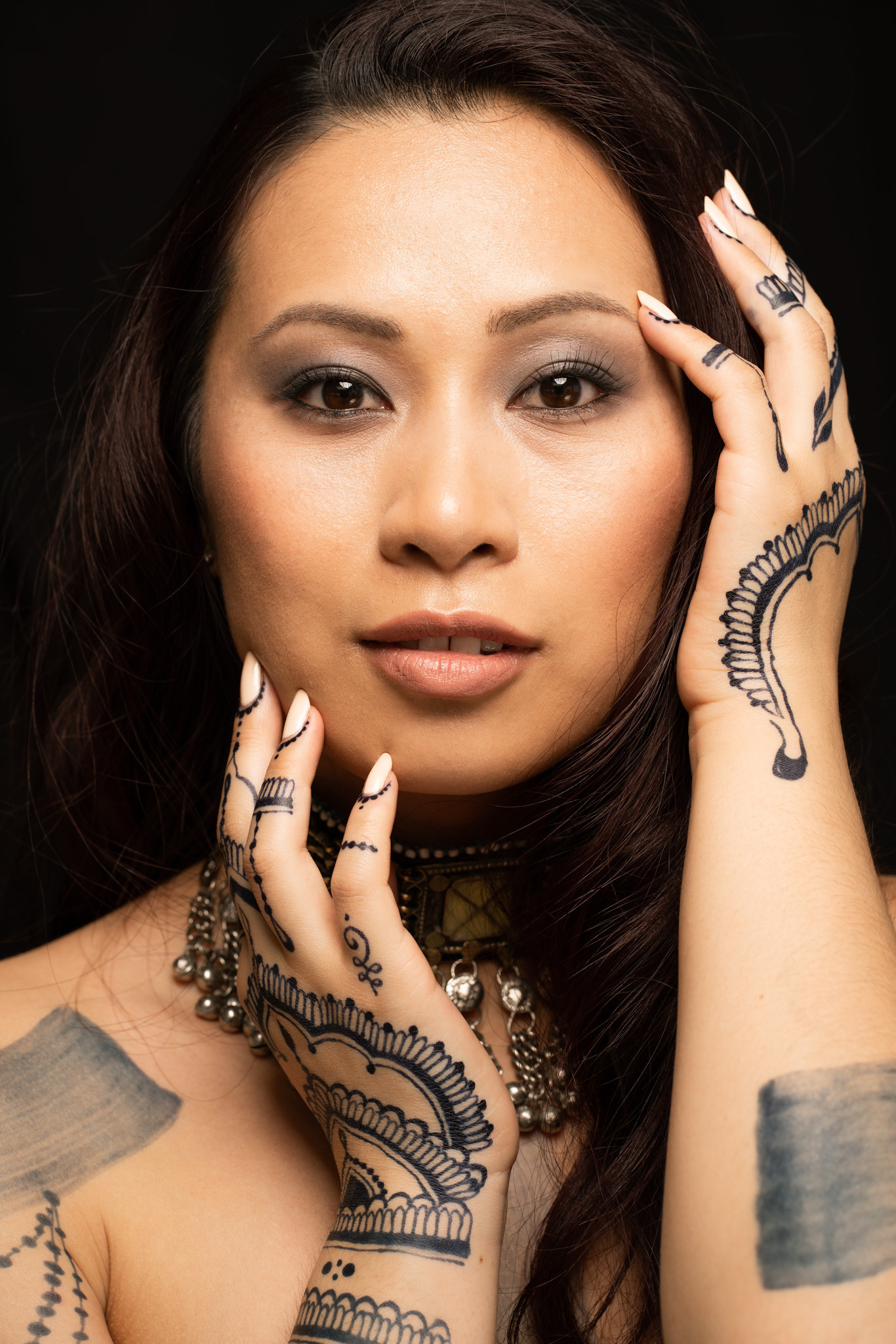 portrait with jagua henna bodyart, hands are close to the face
