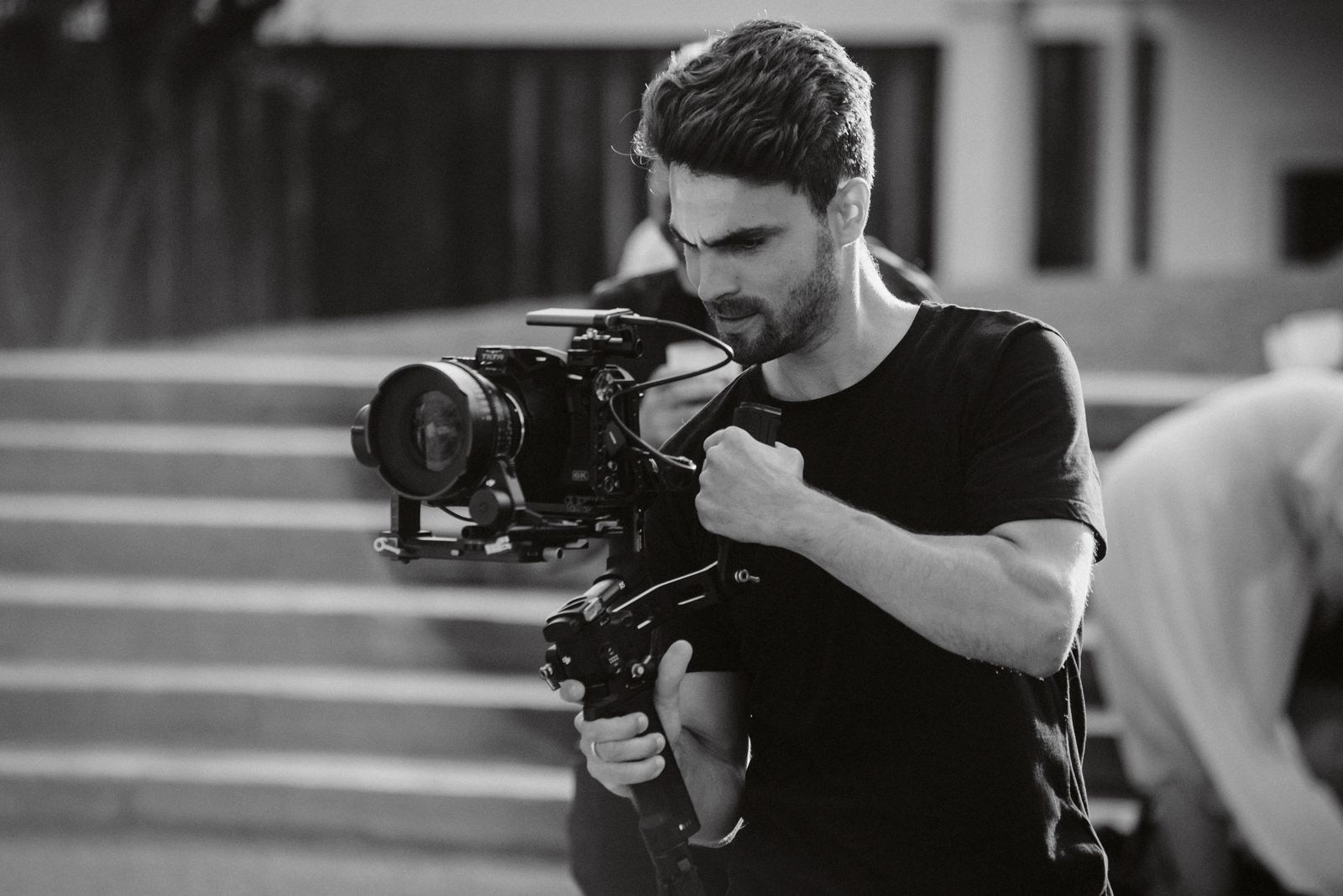 Bastidores de gravação da Beyond Creative na rua, Ricardo a filmar com gimbal e Blackmagic 6K Pro, foto preto e branco.